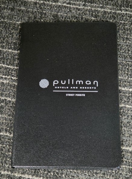 Black Pullman Hotels and Resorts folder on gray carpet—ideal for client gifts or financial planners.