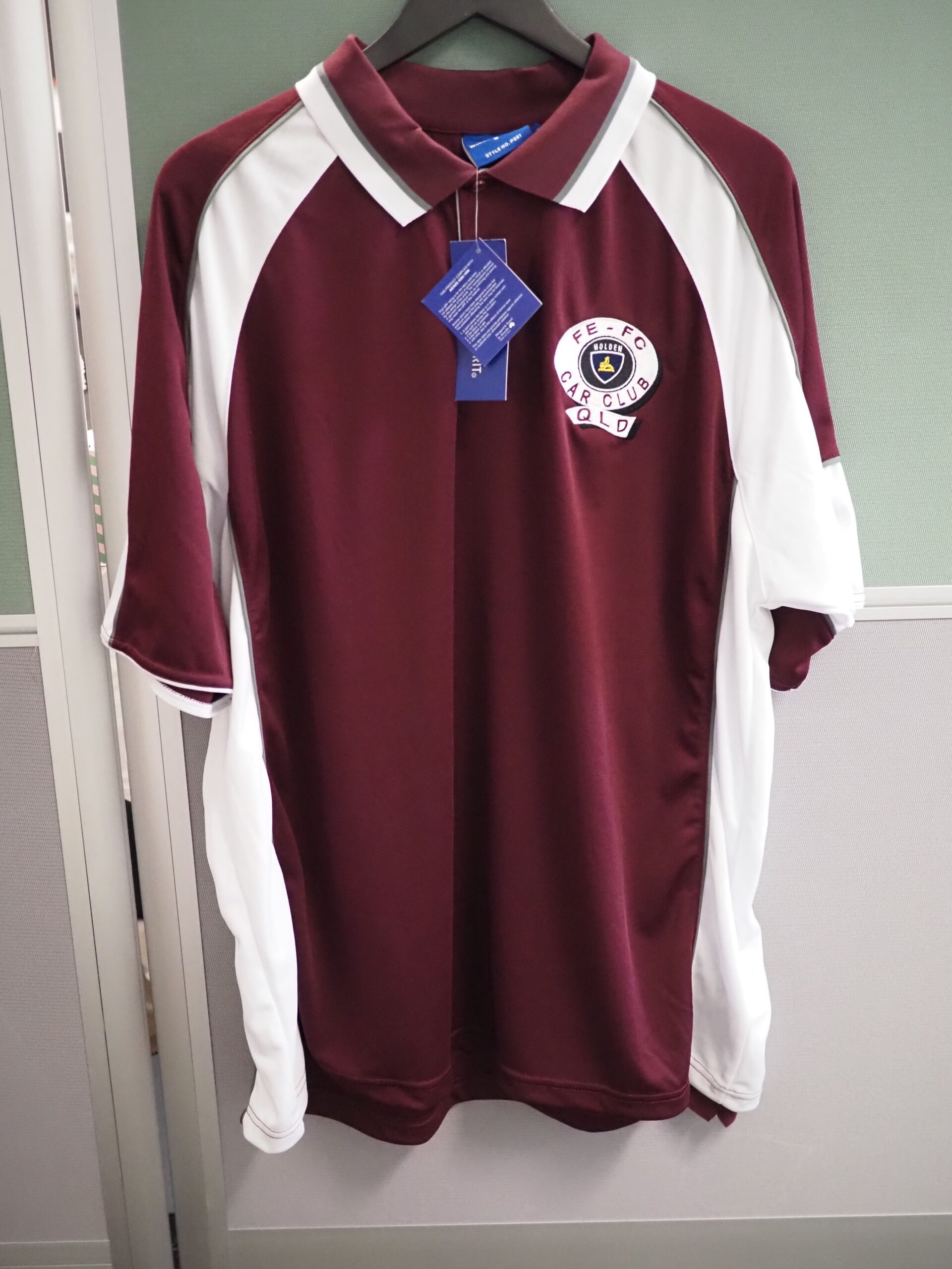 A maroon and white polo shirt with a crest logo—perfect for showcasing how logos print differently.
